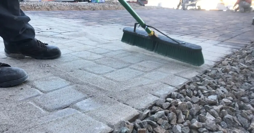 Worker sweeping the newly installed block paving driveway, highlighting the final touches and maintenance for a clean finish.