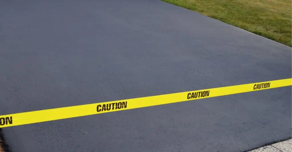 Freshly laid tarmac section cordoned off with caution tape to indicate drying time.